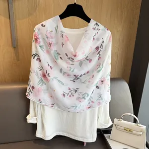 Close-up of lightweight floral scarf with pink blossoms on white semi-transparent fabric