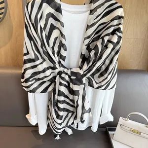 Zebramuster-Schal mit schwarzen Quasten auf weißem Oberteil für einen eleganten Mode-Look