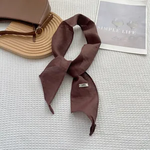 Detailed close-up of dark brown linen scarf with handmade label and natural fiber texture