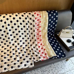 Polka dot silk scarves in black, red and yellow draped elegantly over a modern sofa