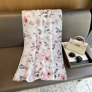 Close-up of floral chiffon scarf with pink petals on white fabric texture