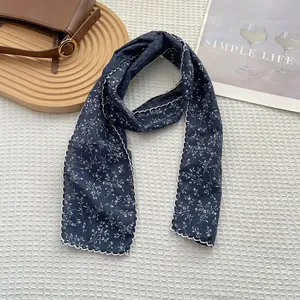 Detail of navy floral cotton scarf with white scalloped edges on a textured background