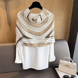 Detail showing the geometric striped cotton shawl texture and elegant layering of the scarf