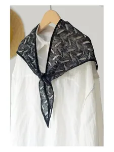 Detail of black hollow lace shawl with stripe texture over a white pleated shirt