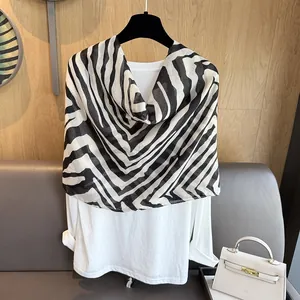 Detail eines Chiffonschals mit Zebramuster über einem weißen Langarmshirt auf einem Bügel