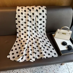 Close-up of white polka dot scarf draped on a leather sofa with chic accessories