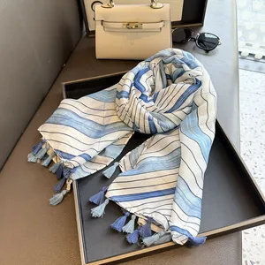 Detail of blue wavy striped scarf with fringe tassels next to an elegant handbag
