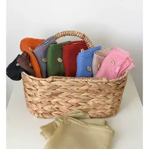 Macro shot of assorted colorful chiffon hijabs with wooden brand tags in a woven basket