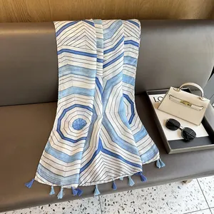 Detail of blue and white striped scarf with tassels draped on a vintage leather sofa