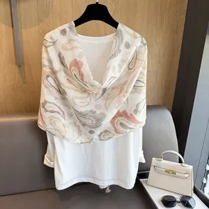 Détail d'une écharpe à motifs bohèmes portée sur un t-shirt blanc minimaliste en coton