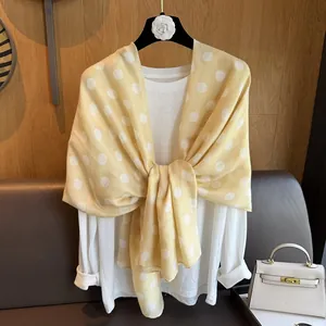 Detail of yellow polka dot silk scarf tied over white long sleeve shirt for women