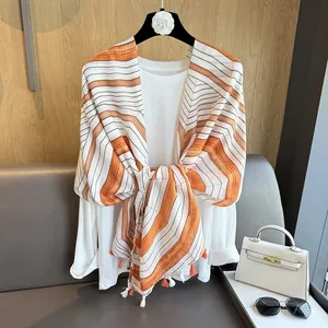 Detail of vintage striped scarf with orange tassels draped over a white blouse