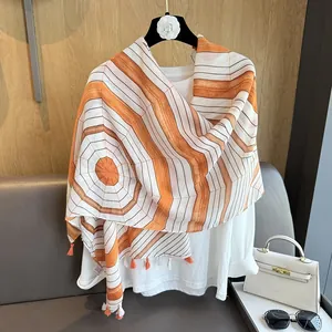 Detail of orange and white geometric striped scarf with tassels on a hanger