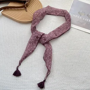 Dettaglio di sciarpa stretta a fiori con nappe eleganti su sfondo bianco con trama a nido