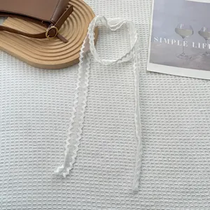 Gedetailleerde close-up van wit kanten lint accessoire op minimalistische achtergrond