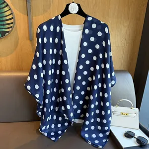 Detail view of a navy blue polka dot chiffon scarf styled with white casual attire