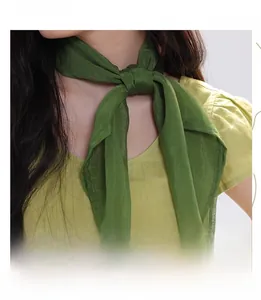 Detail showing high-quality dark green silk-like neck scarf worn with a stylish knot