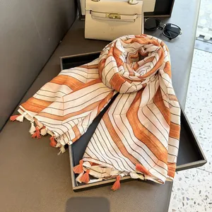 Close-up of geometric striped scarf with tassels on display tray with sunglasses