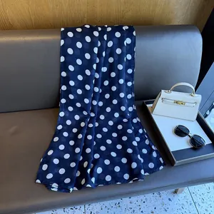Close-up of a navy blue polka dot silk scarf on a brown leather bench with accessories
