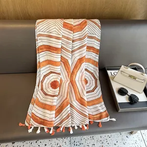Detail of geometric pattern scarf with fringe, sunglasses, and bag on a sofa