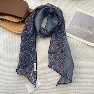 Elegant navy blue striped silk scarf with floral patterns displayed on textured fabric