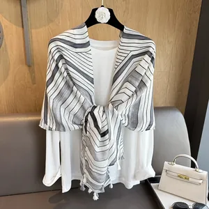 Close-up of black and white striped scarf with tassels and a white long sleeve shirt