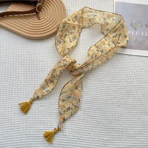 Dettaglio di un foulard in seta gialla a fiori con nappe su un tessuto a quadretti