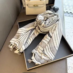 Detail of geometric striped cotton scarf with tassels on a display tray with sunglasses