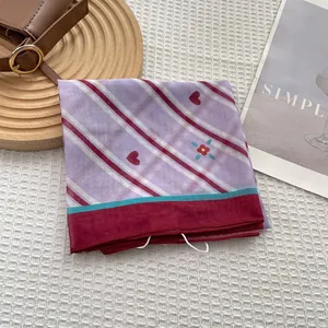 Detailed view of pink heart patterned silk scarf with red stripes on a wooden tray