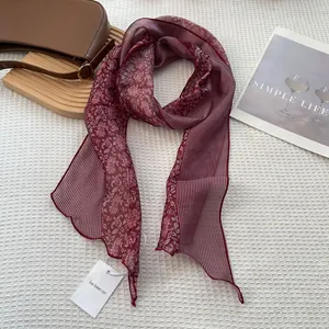 Detailed macro view of burgundy floral striped silk scarf with a branded paper tag