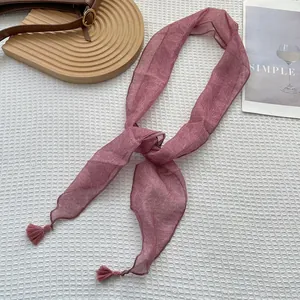 Dettaglio macro della sciarpa in seta rosa antico con motivi a foglia e nappe decorative