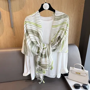 Detail of green striped linen scarf with tassels styled on a white shirt