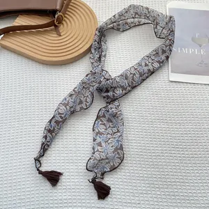 Dettaglio foulard stretto a fiori blu con nappe su sfondo bianco a nido d'ape