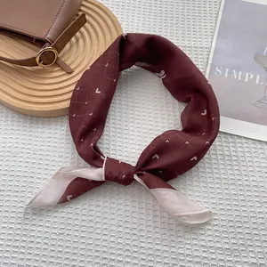 Detail of burgundy heart-pattern silk scarf knotted on a stylish wooden tray