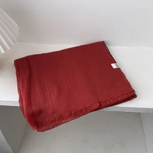 Detalle de bufanda de lino rojo oscuro con textura arrugada y bordes deshilachados