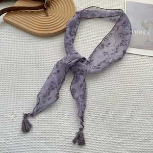 Dettaglio della sciarpa in seta viola a fiori con rose e nappe decorative con frange