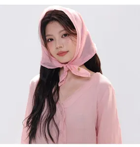 Detail of light pink faux silk square scarf tied in vintage style around model neck