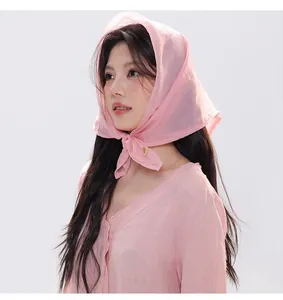 Detail of light pink sheer square scarf with elegant knotting and gold metal charm