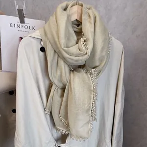 Élégante écharpe en dentelle champagne avec bordure à pompons sur un cintre chic