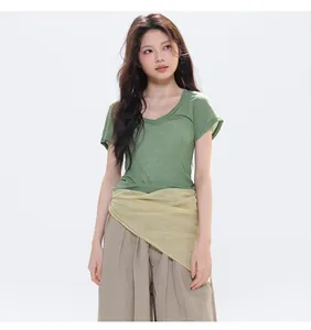 Close-up of a light yellow silk scarf styled around the waist of a green cotton t-shirt