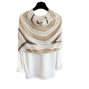 White long sleeve top with geometric patterned shawl and fringe tassels on a hanger