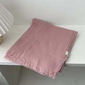 Detalle de bufanda de lino rosa claro con textura arrugada y bordes deshilachados