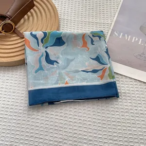 Detailed shot of a floral print silk scarf on a wooden tray with artistic textures