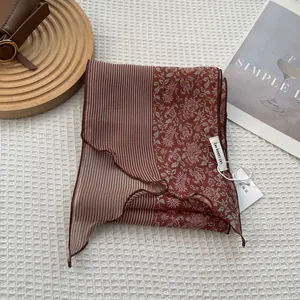 Detail view of brick red striped scarf with vintage floral patterns and wavy edges
