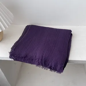 Detalle de bufanda de algodón y lino violeta oscuro con textura arrugada y flecos