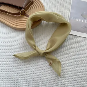 Detail view of light green satin silk scarf with decorative ring tag on waffle fabric