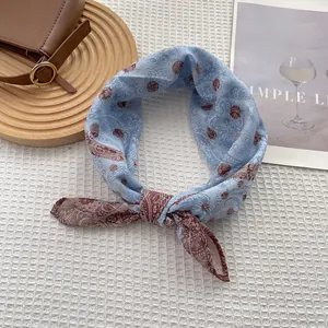 Detailed view of the light blue paisley and polka dot silk scarf tied in a stylish knot