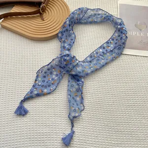 Dettaglio di un piccolo foulard floreale con nappe su uno sfondo a griglia bianca