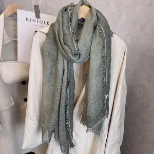 Texture détaillée de l'écharpe en coton et lin vert foncé avec broderie en dentelle