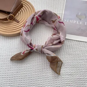 Close-up of pink silk scarf with floral patterns on a textured waffle background